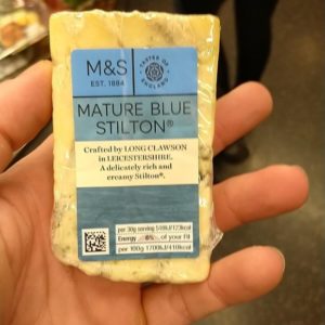 Photo of hand holding cheese, with fingertips visible