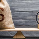 Magnifying glass is looking at the people and a money bag with a dollar sign on the scales. attracting investment, business cooperation, crowdfunding and startup. the cost of specialists and workers