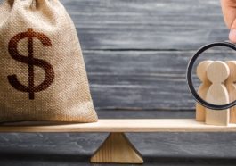 Magnifying glass is looking at the people and a money bag with a dollar sign on the scales. attracting investment, business cooperation, crowdfunding and startup. the cost of specialists and workers