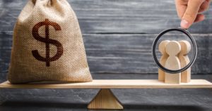 Magnifying glass is looking at the people and a money bag with a dollar sign on the scales. attracting investment, business cooperation, crowdfunding and startup. the cost of specialists and workers