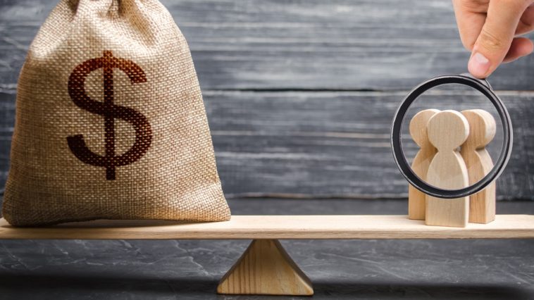 Magnifying glass is looking at the people and a money bag with a dollar sign on the scales. attracting investment, business cooperation, crowdfunding and startup. the cost of specialists and workers