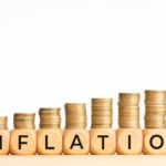 Inflation concept. Text on wooden blocks and stacked coins. Copy space