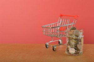 A shopping trolley and coins are a symbolic representation of spending money in shops or making advantageous purchases in shopping centers using currency.
