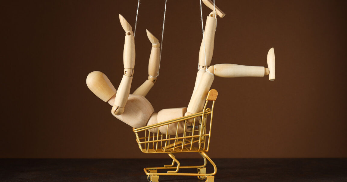 A wooden posable doll sitting in a toy trolley