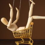 A wooden posable doll sitting in a toy trolley