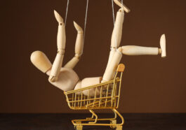 A wooden posable doll sitting in a toy trolley