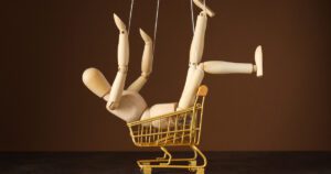 A wooden posable doll sitting in a toy trolley