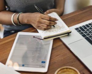 lady writing on notepad with ipad nearby
