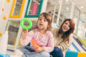 Beautiful mother and daughter having fun playing in a playroom