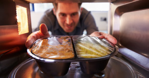 man removing microwaved meal from microwave