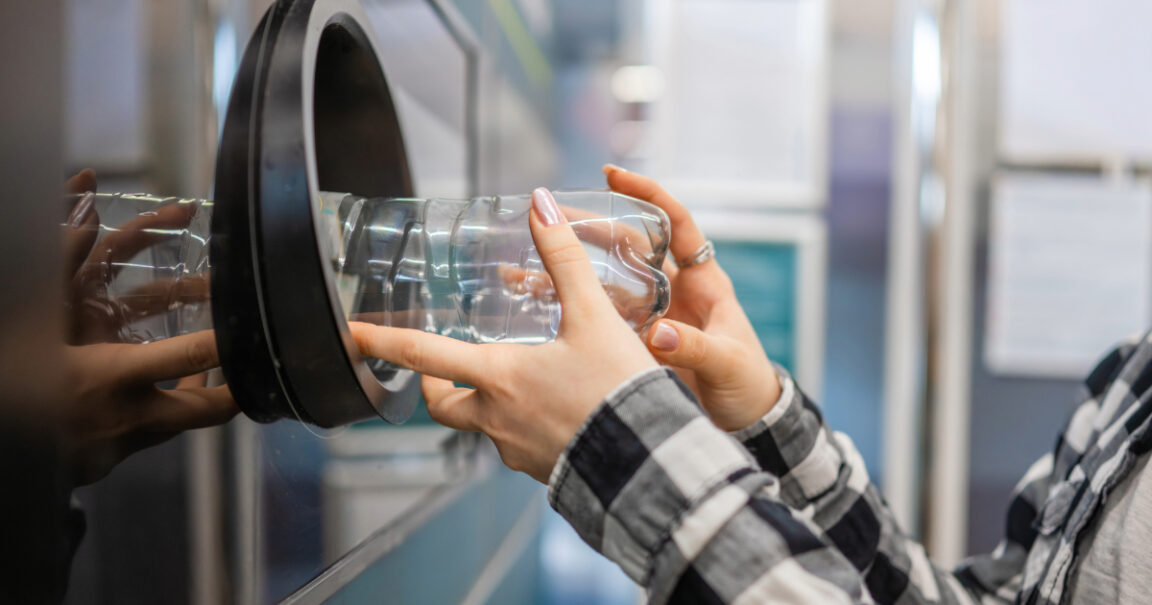 A man placing bottle into recycling machine