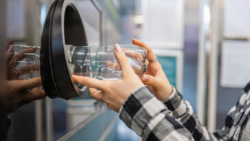 A man placing bottle into recycling machine