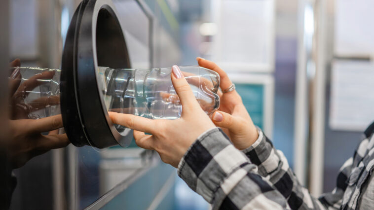 A man placing bottle into recycling machine