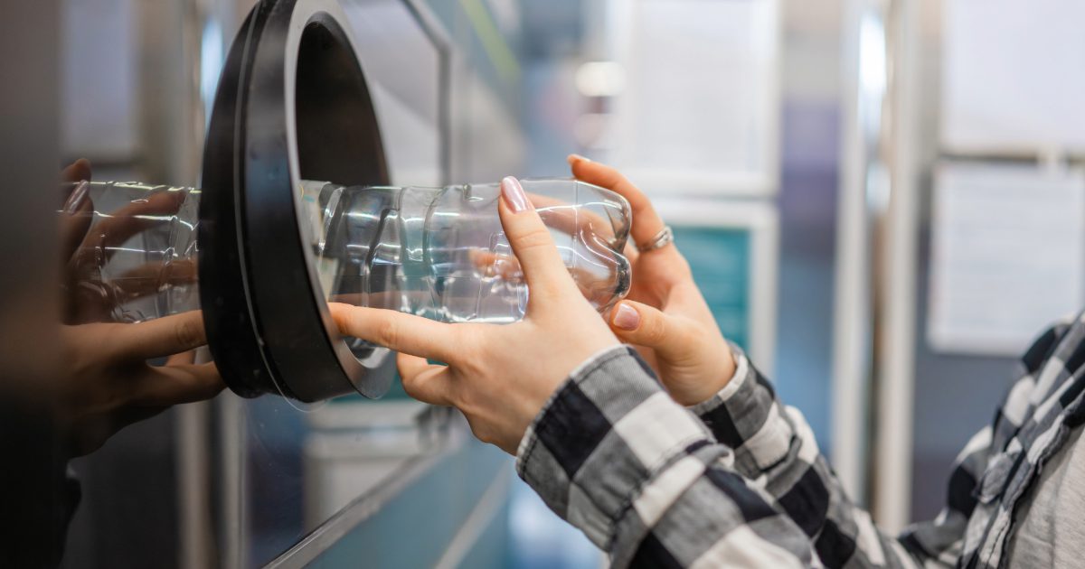 A man placing bottle into recycling machine