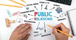 Public Relations concept. Chart with keywords and icons. Hands on working desk doing business