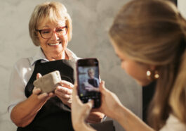 A young women filming a senior woman holding a clay smiling