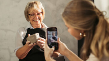A young women filming a senior woman holding a clay smiling