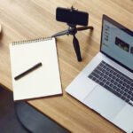 top view of a table with laptop, smartphone, notebook and a cup of coffee on it