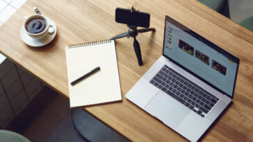 top view of a table with laptop, smartphone, notebook and a cup of coffee on it