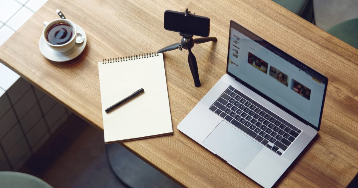 top view of a table with laptop, smartphone, notebook and a cup of coffee on it