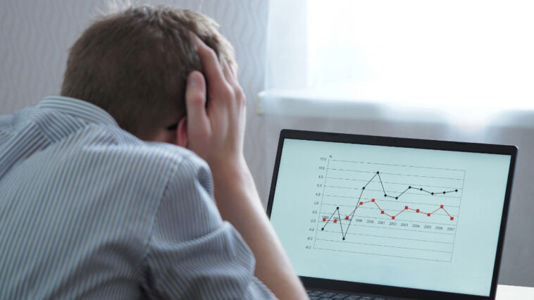 A frustrated man looking at the chart on his laptop